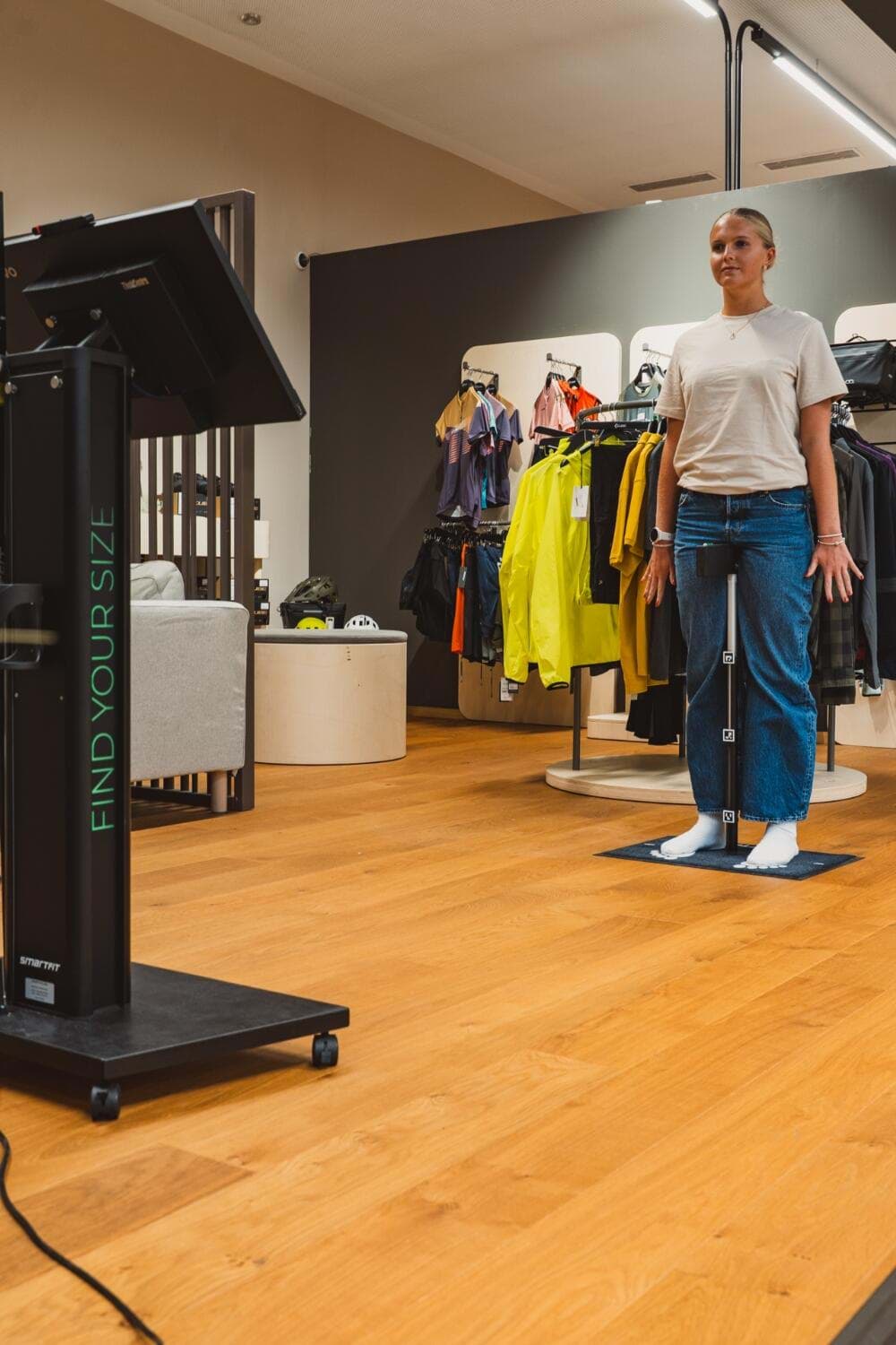 Kundin steht im Store auf der Messmatte und wird an der SmartFit-Messsäule vermessen