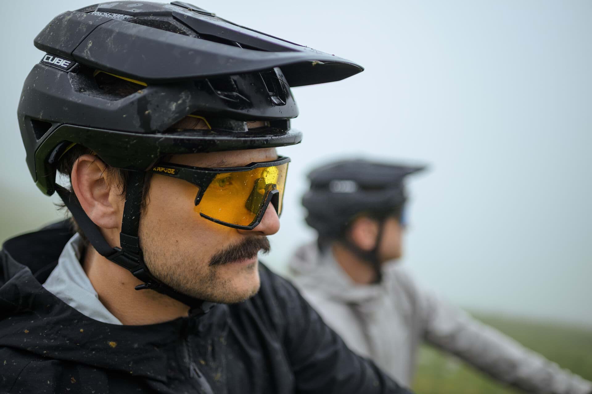Radfahrer mit Helm und Sportbrille, dahinter eine zweite Person